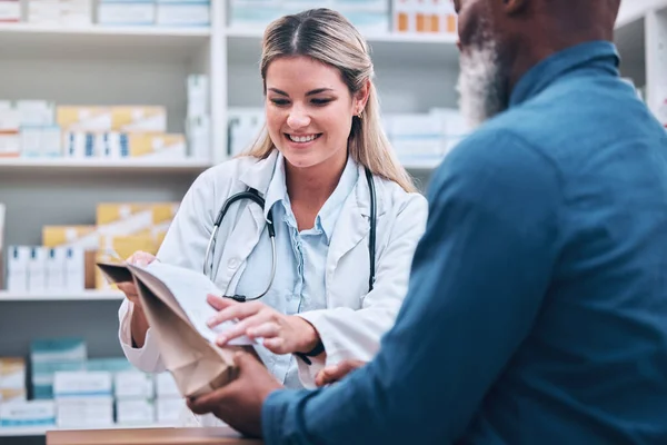 Healthcare, pharmacist and man at counter, medicine, prescription drugs and happy service at drug store. Health, wellness and medical insurance, black man and woman at pharmacy for advice and pills