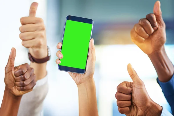 The best app for any business team. a group of businesspeople giving thumbs up and holding a mobile phone in a modern office