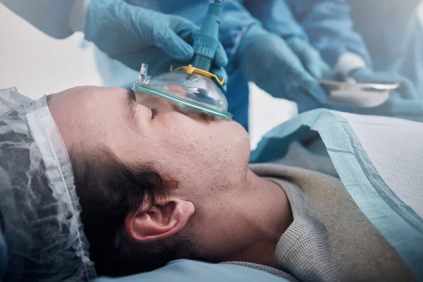 Anesthesia, oxygen mask and medical with man in surgery for breathing, ventilation and operation. Healthcare, cardiology and paramedic with face of patient and doctors in operating room for emergency.