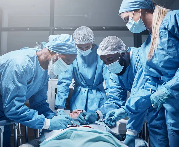 Doctors, surgery and collaboration with a medicine team in scrubs operating on a man patient in a hospital. Doctor, nurse and teamwork with a medical group in a clinic to perform an operation.