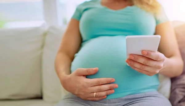 Sending out a countdown to her close ones. Closeup shot of a pregnant woman texting on her cellphone at home