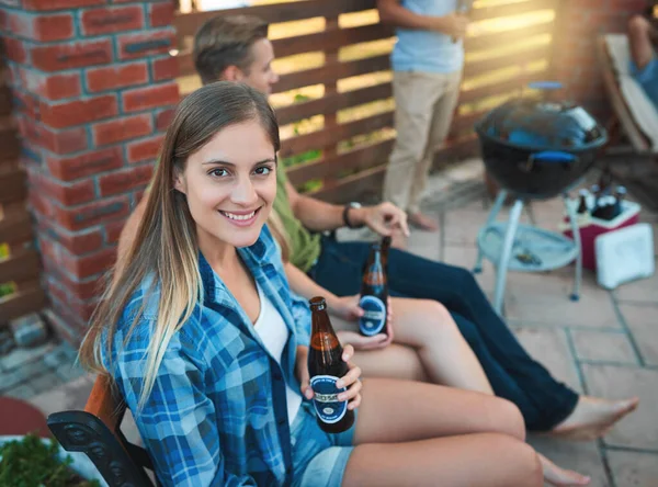 What summer weekends were made for. a happy young woman enjoying a beer at a barbecue with her friends