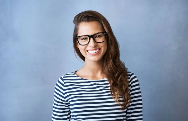 See the good. Studio portrait of an attractive young woman wearing glasses against a blue background