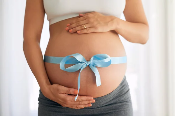 We made a wish and you came true. a woman with a blue ribbon tied around her pregnant belly