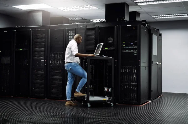 Updating your software. Full length shot of an IT technician using a computer while working in the server room of a data center