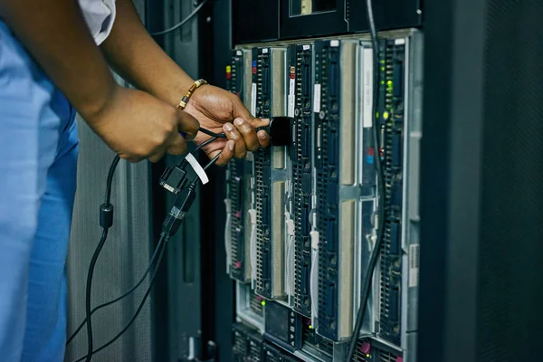 Plugged in to professional IT administration. an IT technician plugging cables into a computer in a data center