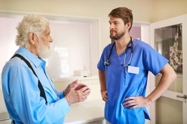 Outlining his symptoms clearly. a senior patient consulting with his doctor in the hospital