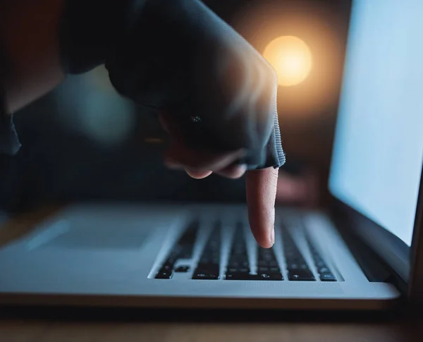 Private information may not be as safe as you think. an unrecognisable hacker using a laptop in the dark