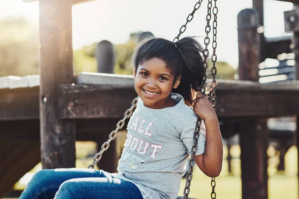 Being young means having days of fun. Cropped portrait of an adorable little girl playing on a swing at the park