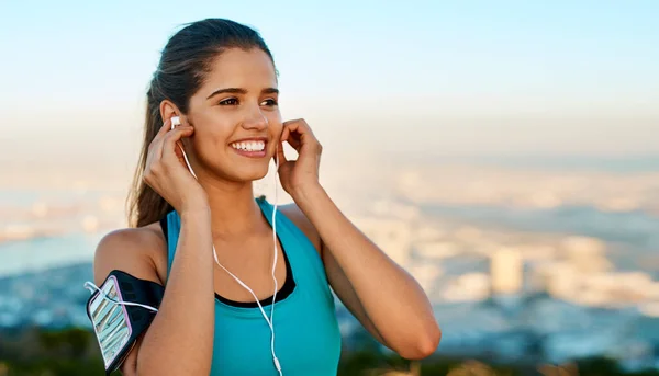 Music makes you feel good when you really need it. a young woman listening to music while out for a run
