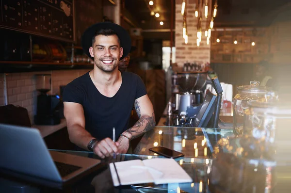 Its hard work but it has a lot of rewards. a handsome young man working behind the counter of a coffee shop