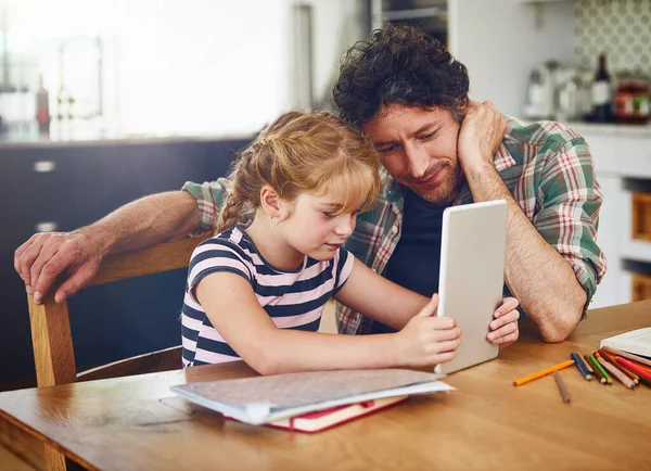Doing some online research for her homework assignment. a father helping his daughter complete her homework on a digital tablet