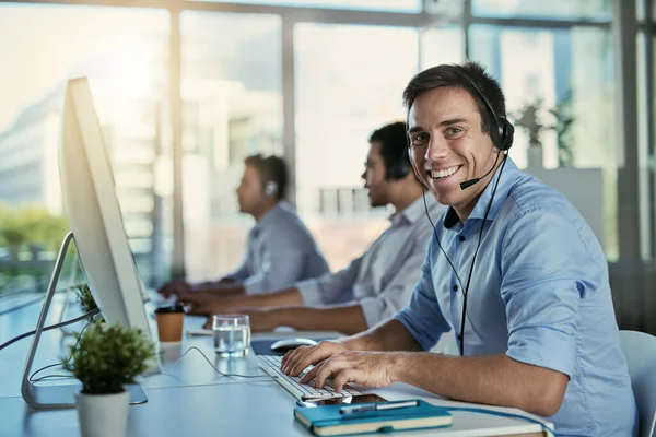 Professional and helpful is the service we stand for. Portrait of a call centre agent working in an office with his colleagues in the background