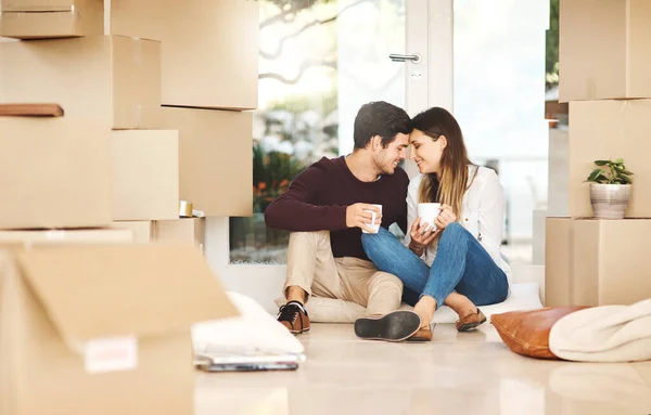 Home really is where the heart is. an affectionate young couple taking a coffee break while moving into a new home