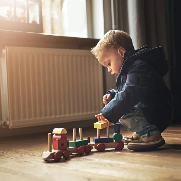 The choo-choo is his favourite toy. an adorable little boy playing with his toy train at home