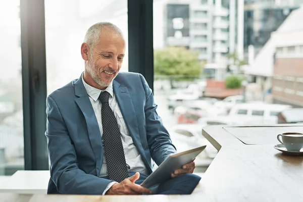 Working in a paperless office to match a modern business. a mature businessman working on a digital tablet in a modern office