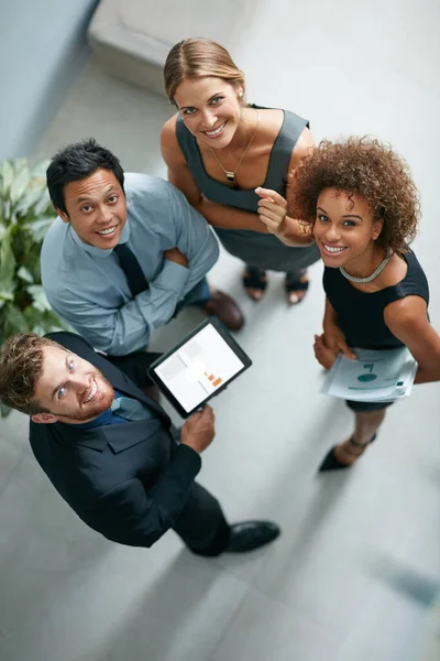 Weve got business covered. High angle portrait of a group of businesspeople talking together over a digital tablet in a modern office