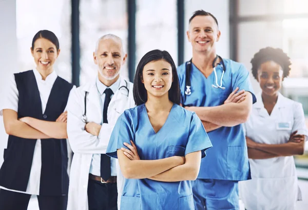 My team and I are focused on your health. Cropped portrait of an attractive female doctor standing with her arms folded with her team behind her