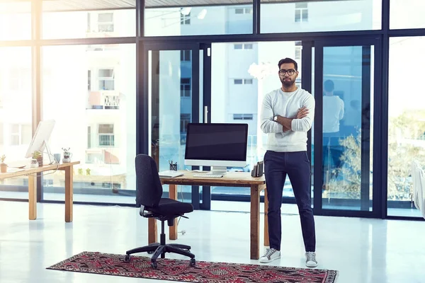 Thinking about the future of his company. Full length shot of a young man leaning against a desk in his office