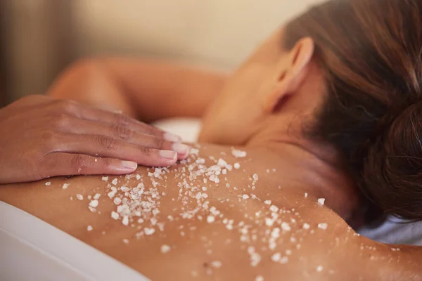 Skincare, spa and woman with salt, luxury and massage back at resort. Female enjoy scrubbing, lady and beauty salon to relax, health and dermatology for exfoliating, skin wellness and natural care