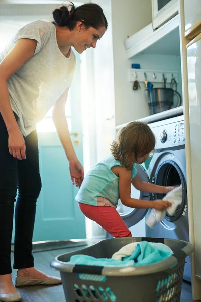 Loading the washing machine. a mother and daughter using a washing machine