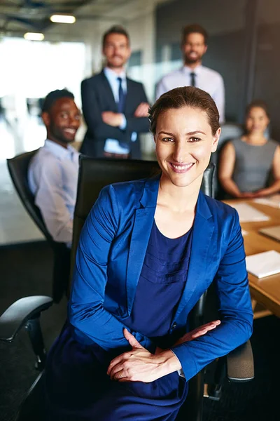 It takes all type to achieve success. Portrait of a smiling businesswoman sitting in an office with colleagues in the background