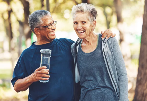 Exercise, senior couple in park and water bottle for training, workout and smile. Mature man, elderly woman and hydration for practice, cardio and energy for wellness, health and fitness in nature