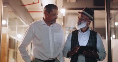 Partnership, tablet and businessmen walking in the office analyzing, talking and planning a project. Technology, professional and senior male employees working on a mobile device in the workplace