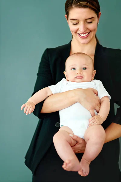 Family and business, she makes it work. Studio shot of a successful young businesswoman carrying her adorable baby boy