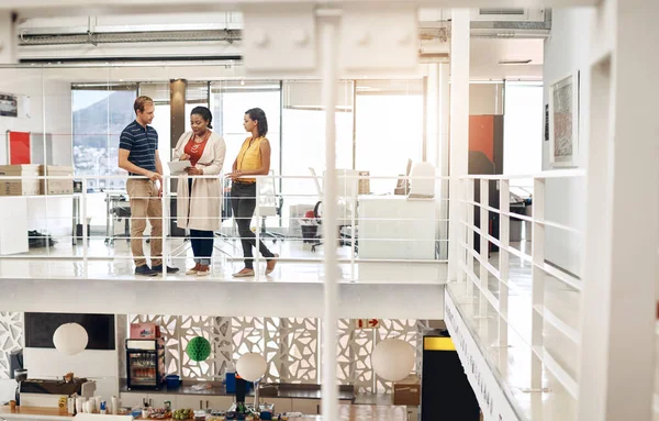 We get work done anywhere in the office. Full length shot of a diverse group of businesspeople standing and using a tablet by the railing of an office
