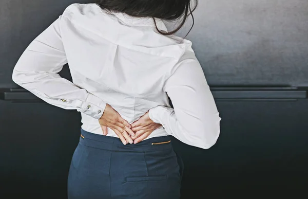 Time to get back to healthy work habits. a businesswoman holding her lower back in discomfort