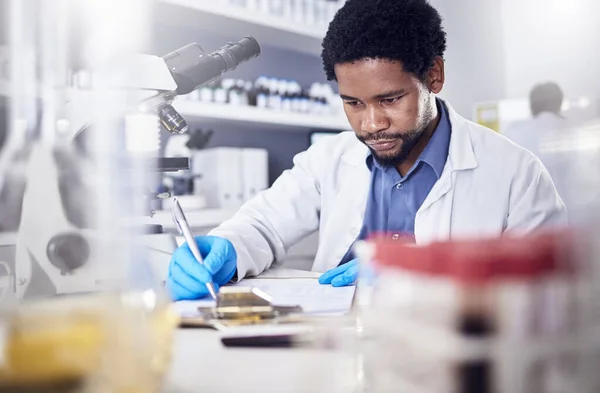 Black man writing report for science study, scientist in lab for research to test and experiment for scientific innovation. Biotechnology in laboratory, focus and knowledge, pen and checklist