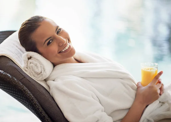 Calm waters, calm mind. a young woman drinking a glass of orange juice at the day spa