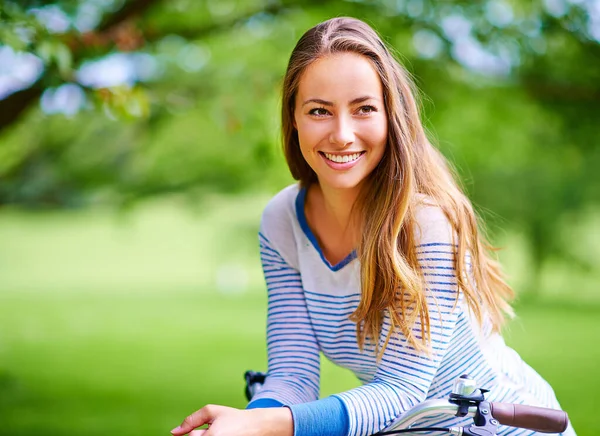 Lovely day to be outdoors. Portrait of a young woman cycling in the park