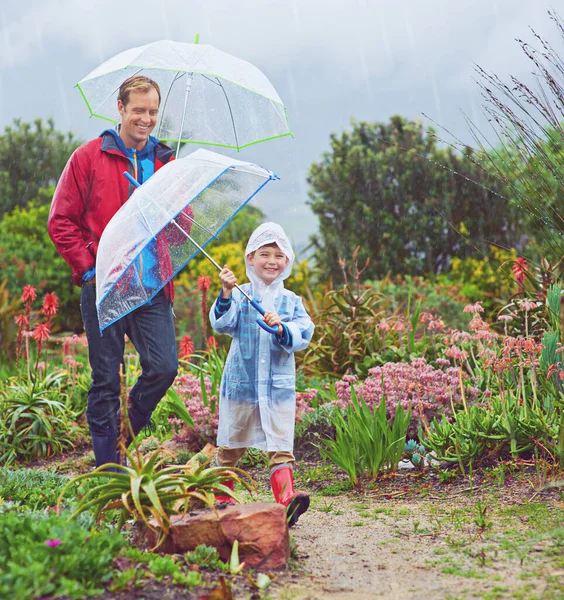 Our garden loves the rain. Full length shot of a father and his son walking outside in the rain