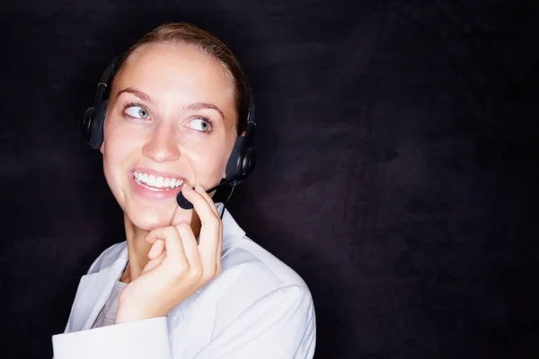 Happy business woman with a headset on black. Smiling young business woman with a headset isolated against black background