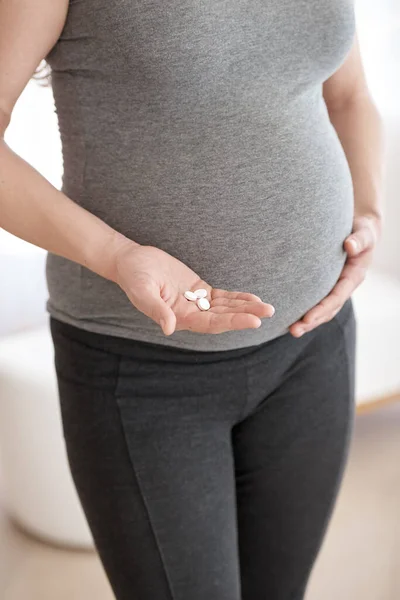 Antenatal vitamins. a pregnant woman holding tablets while standing in her home