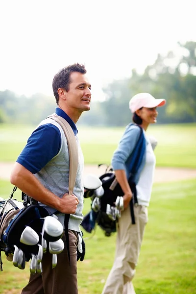 Man and woman carrying golf bags. Man and woman carrying golf bags and looking away