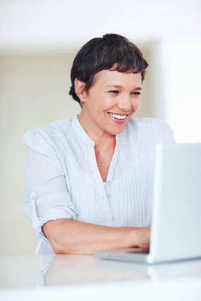 Happy female executive using laptop. Happy mature business woman using laptop at office desk