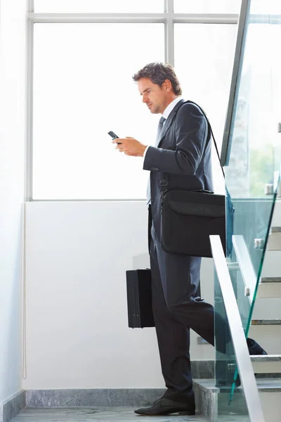 Business man using cellphone on stairs. Full length of handsome middle aged business man using cellphone on stairs