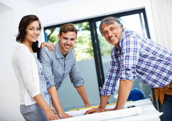 Couple discussing with contractor in office. Portrait of mature contractor with attractive couple smiling in office
