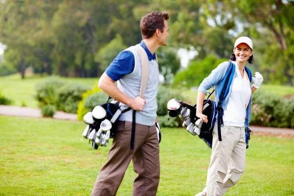 带着高尔夫球袋的夫妇 情侣们背着高尔夫球袋 互相望着对方 — 图库照片
