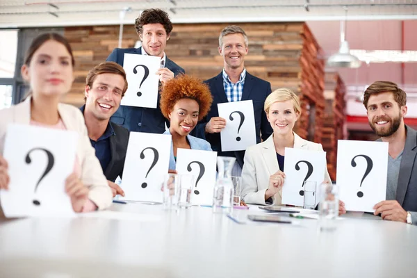 We have the answers to all your questions. Portrait of a group of businesspeople holding up cards with question marks on them