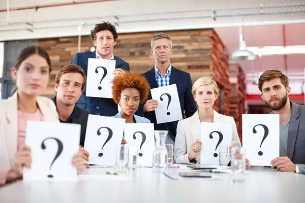 Any questions. Portrait of a group of businesspeople holding up cards with question marks on them