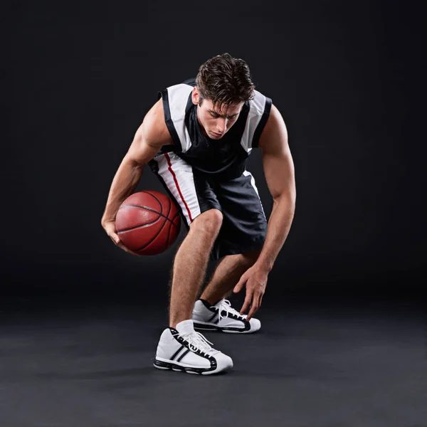 Mastering the game. Full length shot of a male basketball player in action against a black background
