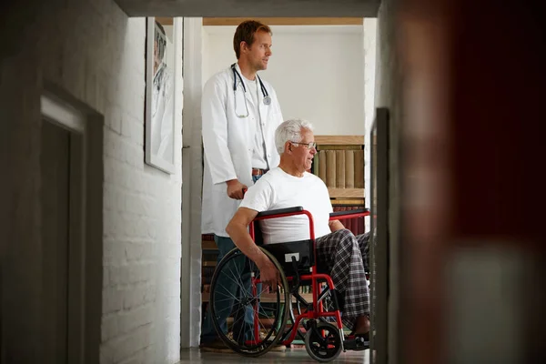 Its all about your outlook on life. a male doctor standing with his senior patient whos in a wheelchair