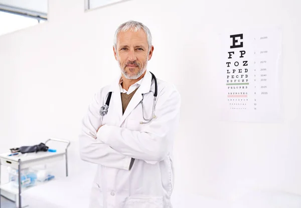 Can you read whats on the chart Lets see. Portrait of a mature male optometrist standing in his office with an eye chart in the background