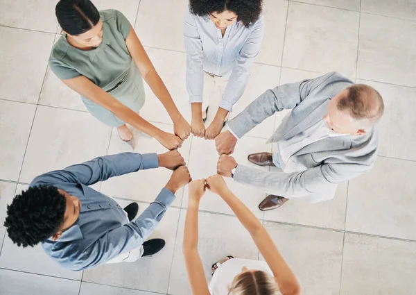 Above, business people and fist bump circle in office for teamwork, motivation and support for success. Corporate group, vision and team building in workplace with diversity, solidarity and mission.