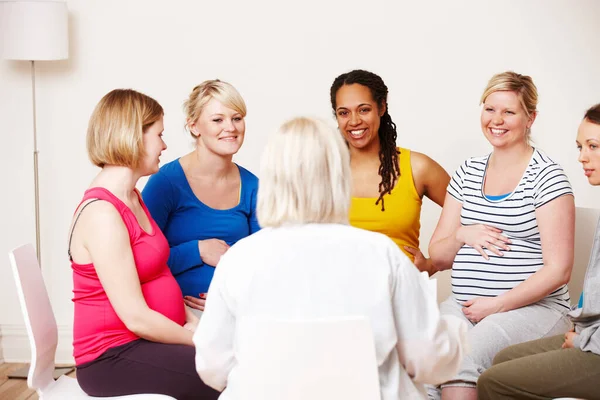 Getting advice from the midwife. A group of pregnant women sitting together in a circle listening while a midwife gives them advice