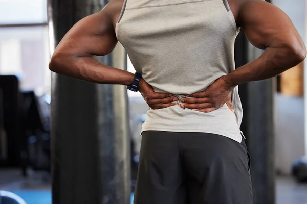 Black man, fitness or back pain in gym workout, exercise or training and body anatomy crisis, muscle burnout or spinal tension. Sports athlete, personal trainer or coach with injury or health problem.